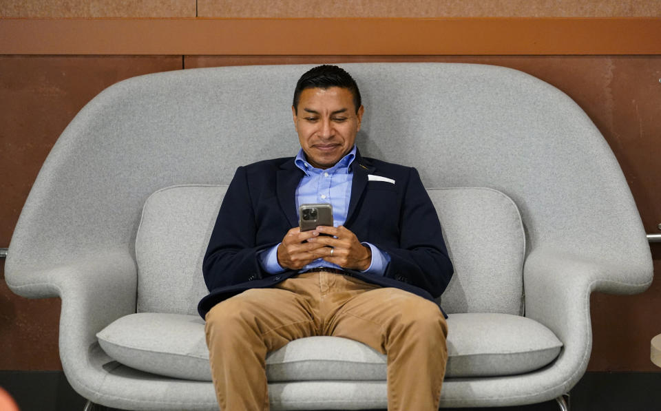 Republican candidate for Indiana Secretary of State Diego Morales checks his phone for messages as he waits for the start of an interview in Indianapolis, Tuesday, Sept. 20, 2022. (AP Photo/Michael Conroy)