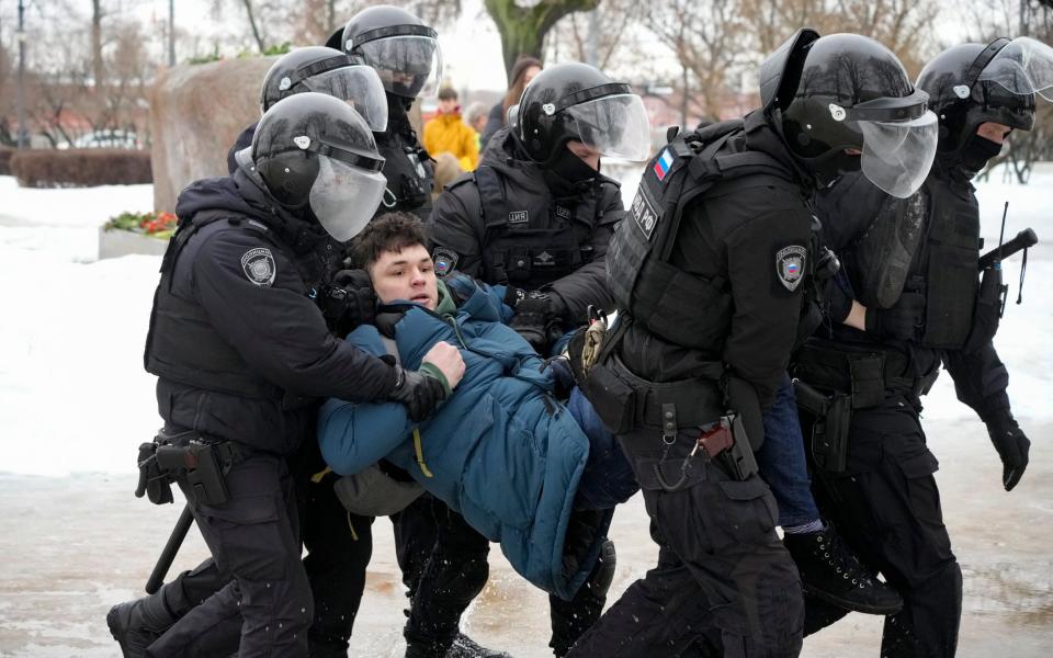 Police detain a man as he wanted to lay flowers paying their last respect to Alexei Navalny at the monument, a large boulder from the Solovetsky islands, where the first camp of the Gulag political prison system was established, in St. Petersburg, Russia on Saturday, Feb 17