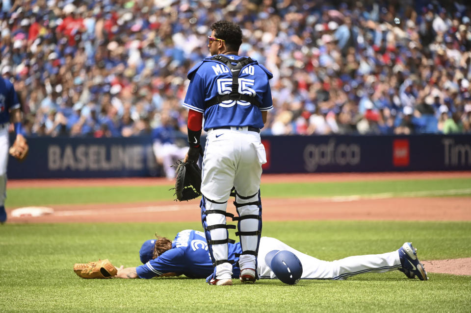 Toronto Blue Jays' catcher Gabriel Moreno (55) checks on starting pitcher Kevin Gausman after Gausman was hit by a batted ball off the bat of a Tampa Bay Rays batter during the second inning of a baseball game, Saturday, July 2, 2022 in Toronto. (Jon Blacker/The Canadian Press via AP)