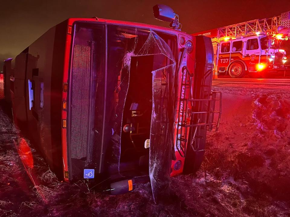 An OC Transpo bus ended up flipped on its side and in a ditch after a collision with another vehicle at Leitrim and Bowesville roads Sunday night. (Ottawa Fire Services - image credit)