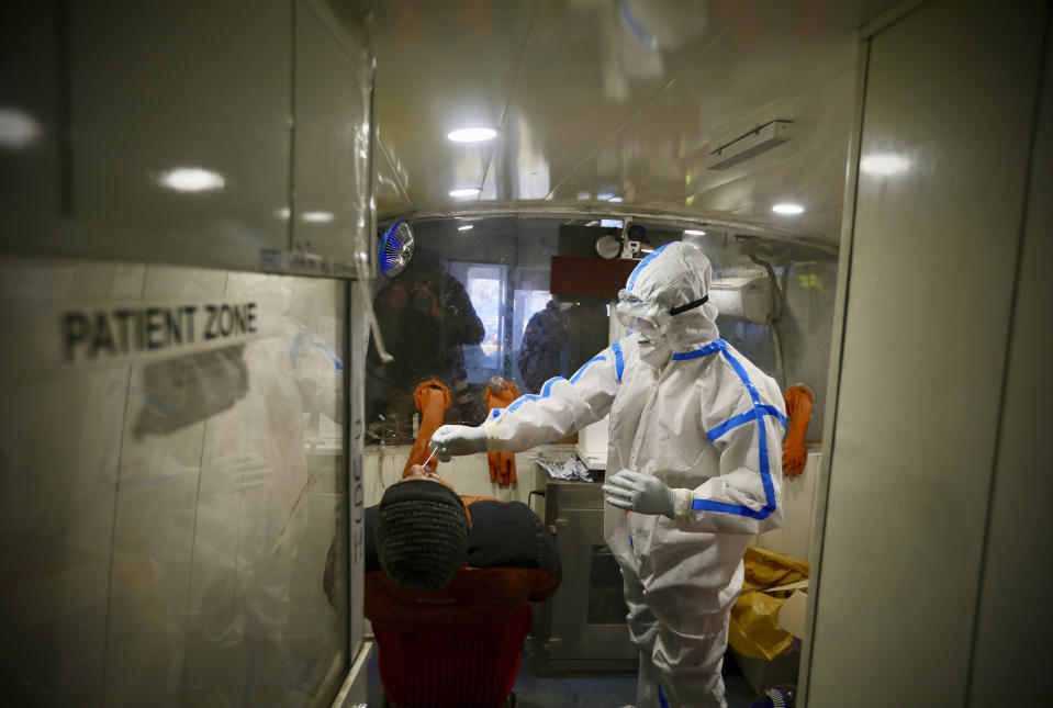 A health worker takes a nasal swab sample to test for COVID-19 inside a mobile testing van in New Delhi, India, Saturday, Dec. 19, 2020. India’s confirmed coronavirus cases have crossed 10 million with new infections dipping to their lowest levels in three months, as the country prepares for a massive COVID-19 vaccination in the new year. (AP Photo/Manish Swarup)