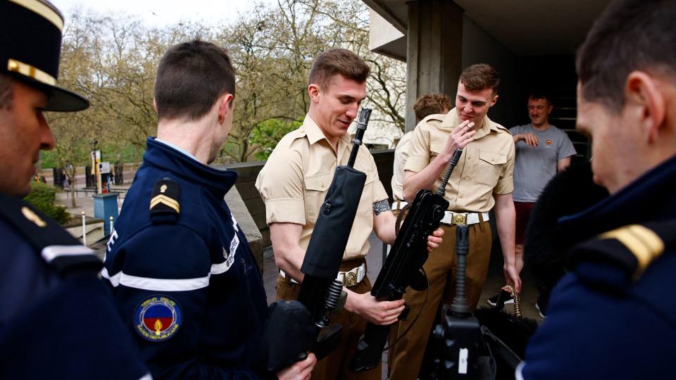 Members of France's Gendarmerie Garde Republicaine and members of the British Army's F Company Scots Guards look at each others' rifles following a rehearsal for a special Changing of the Guard ceremony