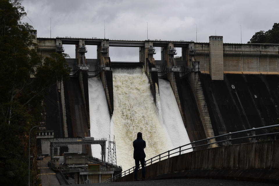 A person watches on as the Warragamba Dam spillway is seen outflowing in Warragamba on Saturday. Source: AAP