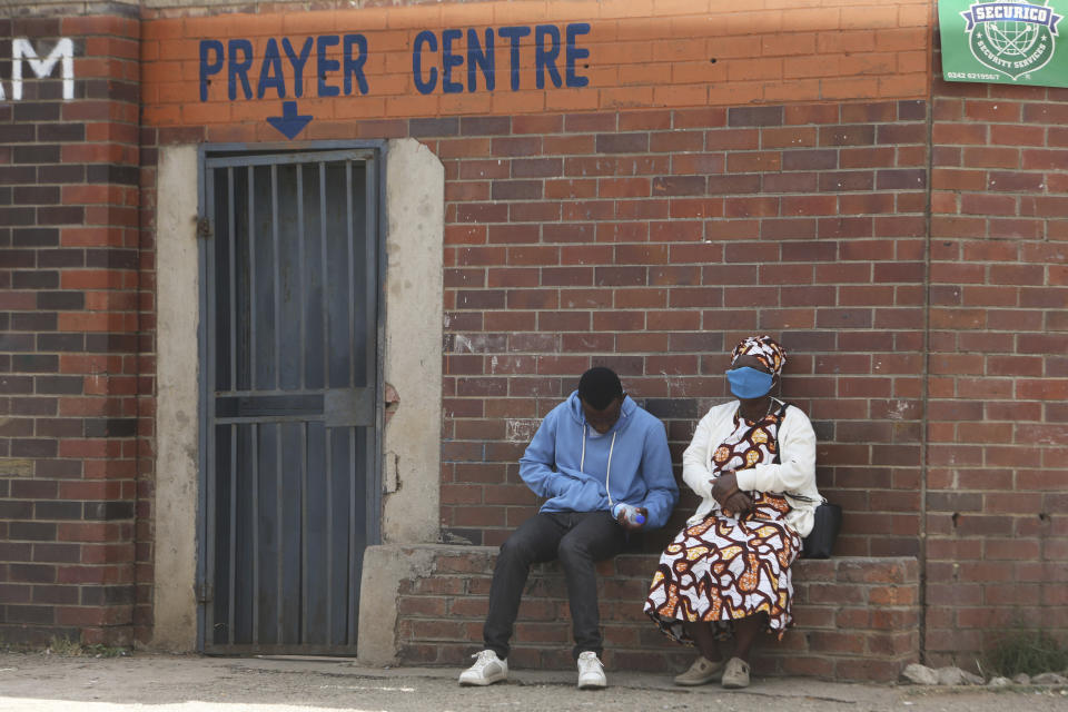 Personas sentadas afuera de un centro de oración en Harare, el jueves 28 de mayo de 2020.(AP Foto/Tsvangirayi Mukwazhi)