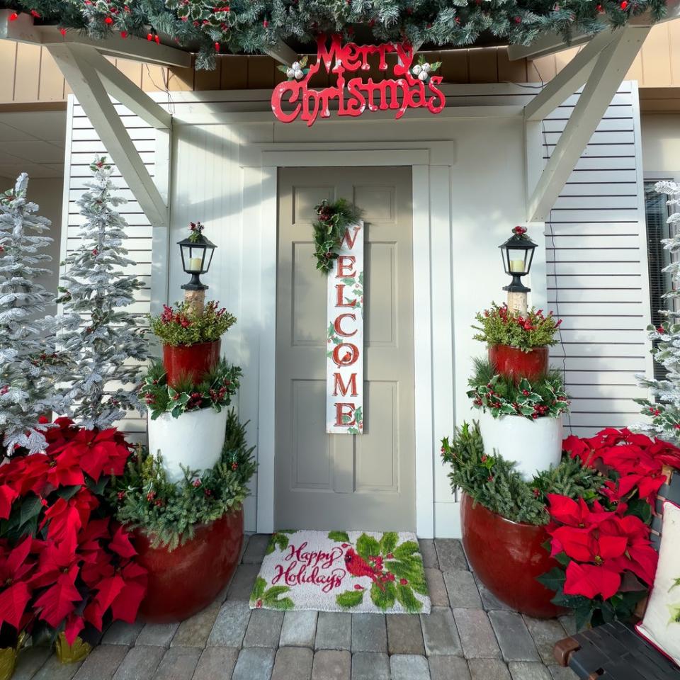 Doorway of home decorated for winter and Christmas with signs and poinsettias.  