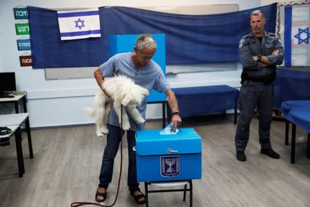 A man holds his dog as he casts his vote in a ballot box during Israel's parliamentary election at a polling station in Rosh Ha'ayin, Israel