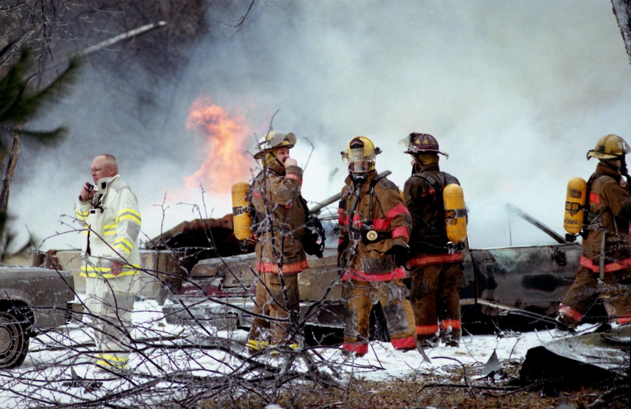 Metro firefighters, with Fire Chief Buck Dozier, left, leading the way, continue to work the scene on Luna Drive after the F-14 Tomcat of Navy Lt. Cmdr. John Stacy Bates slammed into the home of Elmer and Ada Newsom shortly after taking off from Nashville International Airport Jan. 29, 1996.