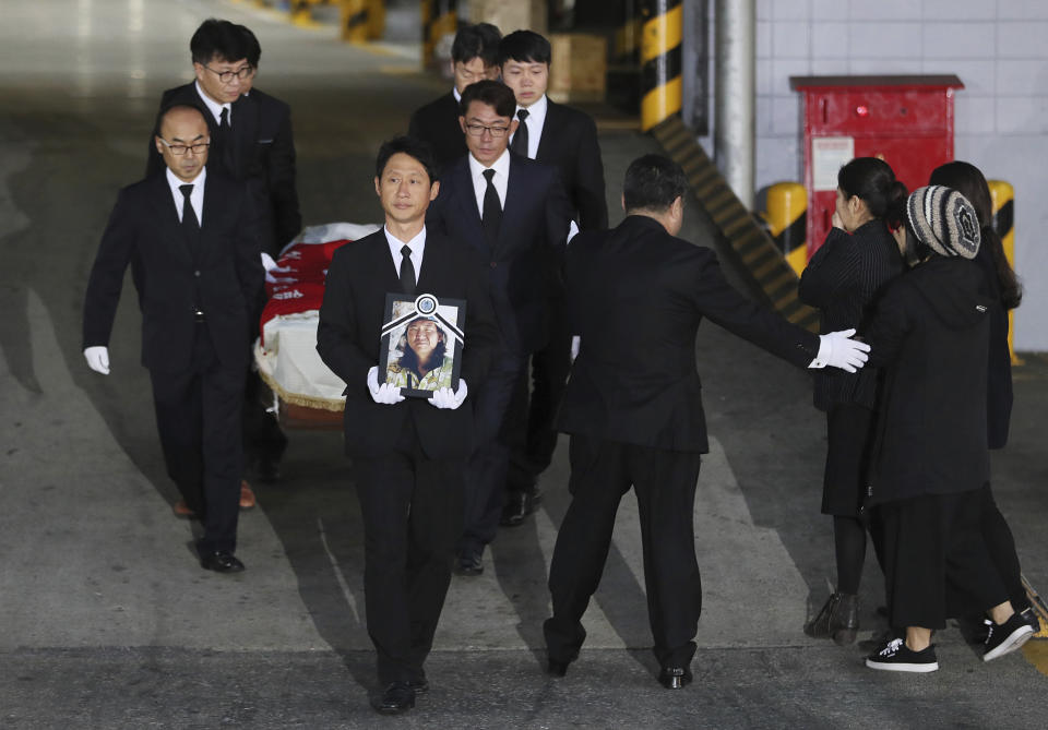 Relatives and friends of late mountain climber Im Il-jin carry his portrait and a casket containing his body from a cargo terminal at Incheon International Airport in Incheon, South Korea, Wednesday, Oct. 17, 2018. Relatives dressed in black funeral suits wept in grief on Wednesday as the bodies of five South Korean mountain climbers arrived home from Nepal where they had died in a storm last week. (Lee Ji-eun/Yonhap via AP)