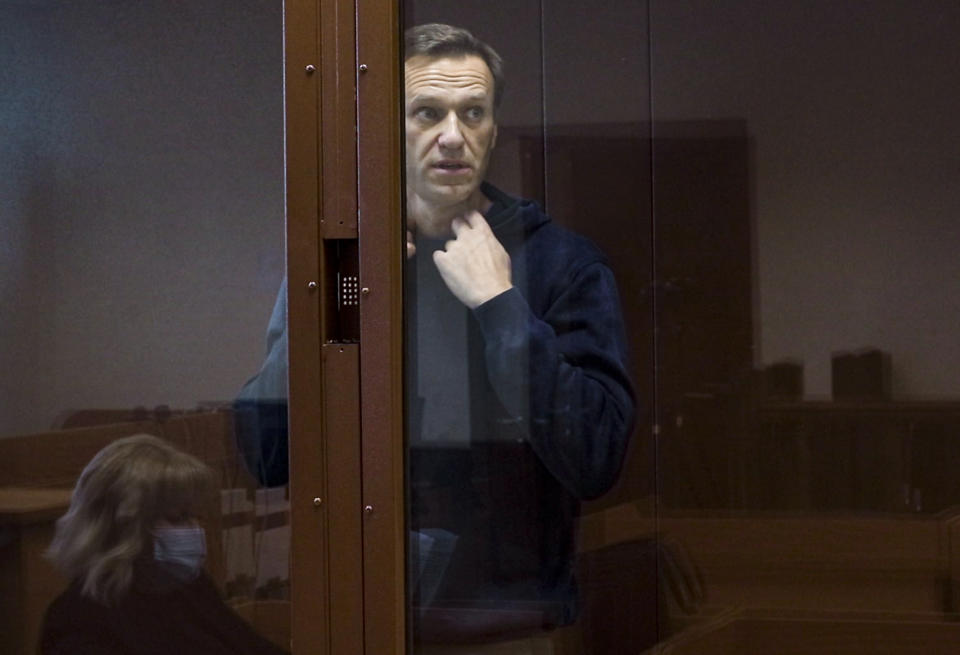 In this photo taken from a footage provided by the Babuskinsky District Court Tuesday, Feb. 16, 2021, Russian opposition leader Alexei Navalny stands in a cage during a hearing on his charges for defamation in the Babuskinsky District Court in Moscow, Russia. Navalny is accused of defaming a World War II veteran who was featured in a video last year advertising constitutional amendments that allowed an extension of President Vladimir Putin's rule. (Babuskinsky District Court Press Service via AP)