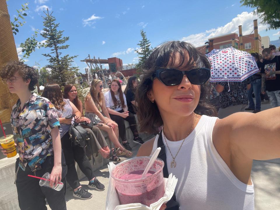 woman holding acai bowl while wearing sunglasses and waiting in line for Jeffree Star Store