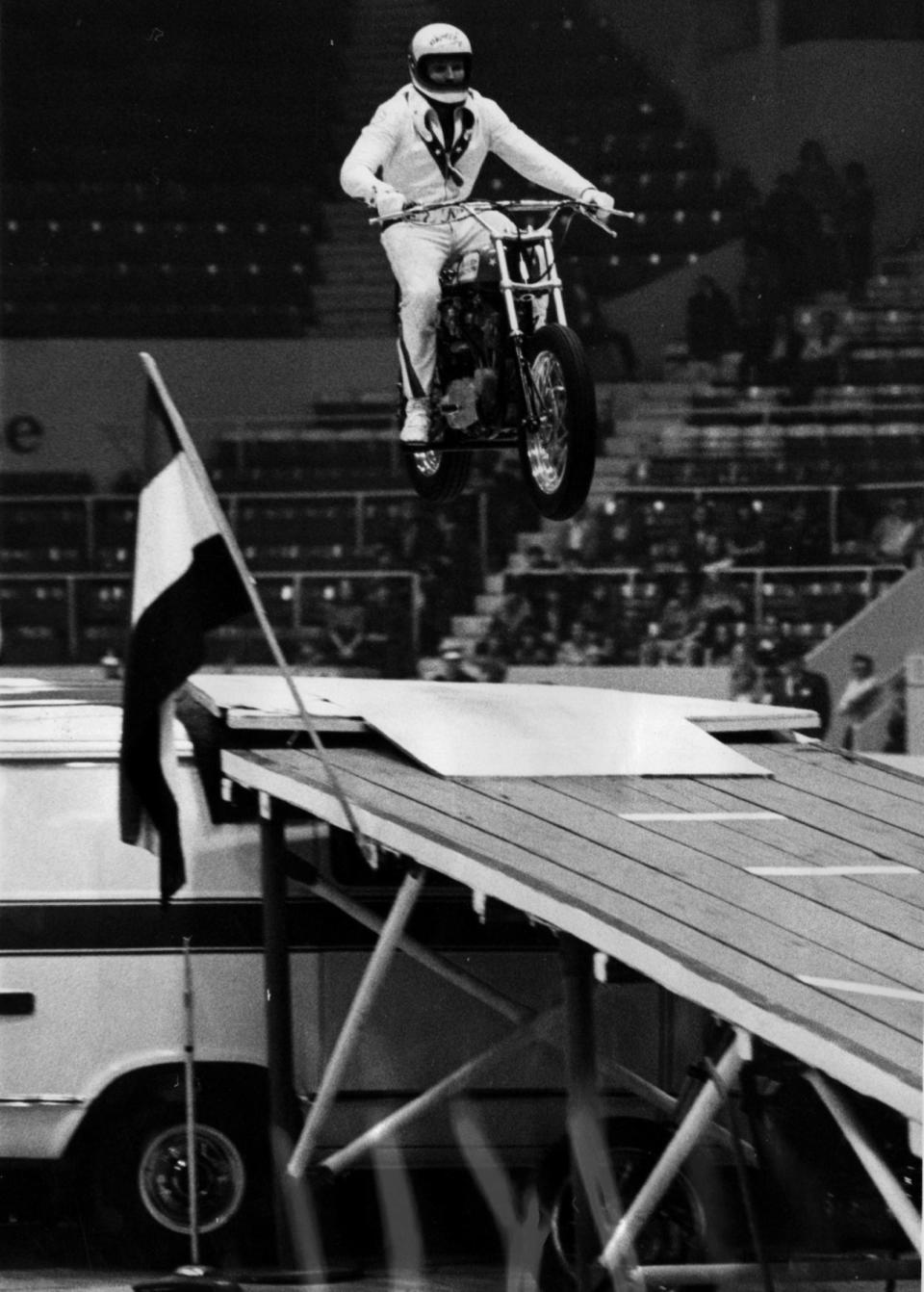 Daredevil stunt rider Evel Knievel is about to hit the landing ramp after sailing over a collection of cars and trucks during one of his performances at the Cincinnati Gardens in 1973.