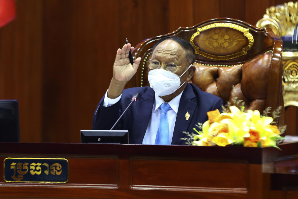 In this photo released by Cambodia's National Assembly, Cambodian National Assembly President Heng Samrin hands up as he sits for leading lawmakers session in the National Assembly hall in Phnom Penh, Cambodia, Monday, Oct. 25, 2021. Lawmakers in Cambodia on Monday approved amending the constitution to bar Cambodians with dual citizenship from holding high government office, a move initiated by Prime Minister Hun Sen.(Cambodia's National Assembly via AP)