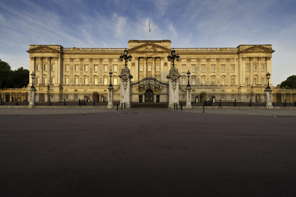 London, UK - May 3th, 2011: Warm dawn sunlight illuminated the Portland stone facade, windows, balcony and ornate entrance gates of Buckingham Palace, London residence of the British Monarch, from the Victoria Memorial on The Mall.