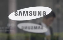 FILE - In this April 30, 2019, file photo, an employee walks past a logo of the Samsung Electronics Co. at its office in Seoul, South Korea. Pressure is mounting on South Korean President Moon Jae-in to pardon Samsung heir Lee Jae-yong, who is back in prison after his conviction in a massive corruption scandal, even though business has rarely looked better at South Korea’s largest company. (AP Photo/Ahn Young-joon, File)