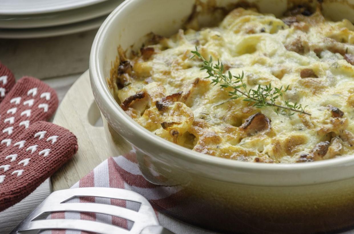 Creamy chicken and potato casserole in stone baking dish with red and white striped kitchen cloth
