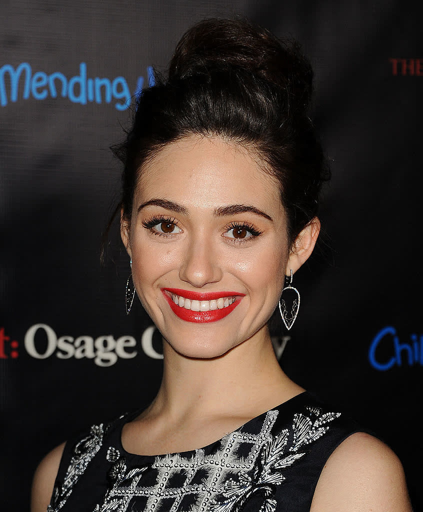 Emmy smiling for the camera, wearing a sleeveless dress with embellished details, hair styled in an updo