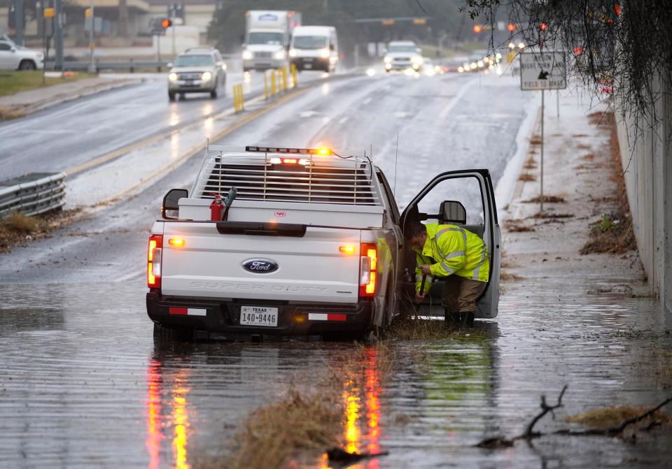 A worker with the City of Austin Watershed Protection Department tries to clear the drainage on Steck Avenue which had to be closed in the westbound lanes near Mopac Boulevard during a rain storm on Jan. 22, 2024.