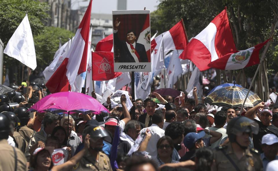 People carry a photo of Peru's late President Alan Garcia that reads in Spanish "Present!" during his funeral procession in Lima, Peru, Friday, April 19, 2019. Garcia shot himself in the head and died Wednesday as officers waited to arrest him in a massive graft probe that has put the country's most prominent politicians behind bars and provoked a reckoning over corruption. (AP Photo/Martin Mejia)