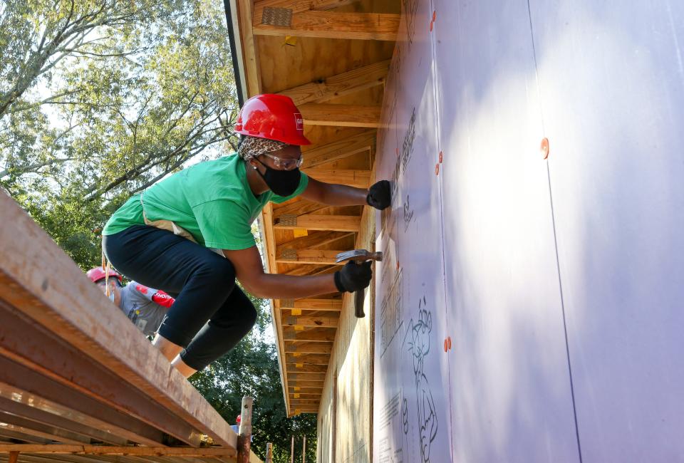 GAF employees work with Habitat for Humanity to blitz build a house in five days on 25th St. in Tuscaloosa Tuesday, Oct. 26, 2021. Verna Smith, the future homeowner, helps nail up the insulation on the exterior walls. [Staff Photo/Gary Cosby Jr.]