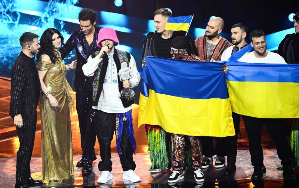 Members of the band &quot;Kalush Orchestra&quot; (C and R) celebrate onstage with Ukraine&#39;s flags as (From L) Italian television presenter Alessandro Cattelan, Italian singer Laura Pausini and Lebanese-born British singer-songwriter, Mika applaud, after winning on behalf of Ukraine the Eurovision Song contest 2022 on May 14, 2022 at the Pala Alpitour venue in Turin. (Photo by Marco BERTORELLO / AFP) (Photo by MARCO BERTORELLO/AFP via Getty Images) - MARCO BERTORELLO/AFP via Getty Images
