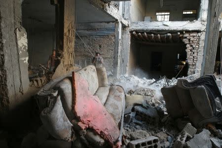 People are seen amid debris at a damaged site in Arbin, a town in Damascus countryside, Syria. REUTERS/Bassam Khabieh