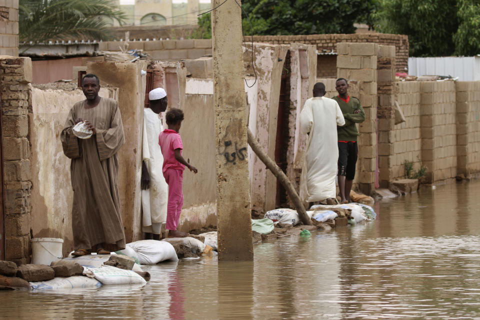 People walk on sandbags to reach their homes in the town of Shaqilab, about 15 miles (25 km) southwest of the capital, Khartoum, Sudan, Monday, Aug. 31, 2020. (AP Photo/Marwan Ali)
