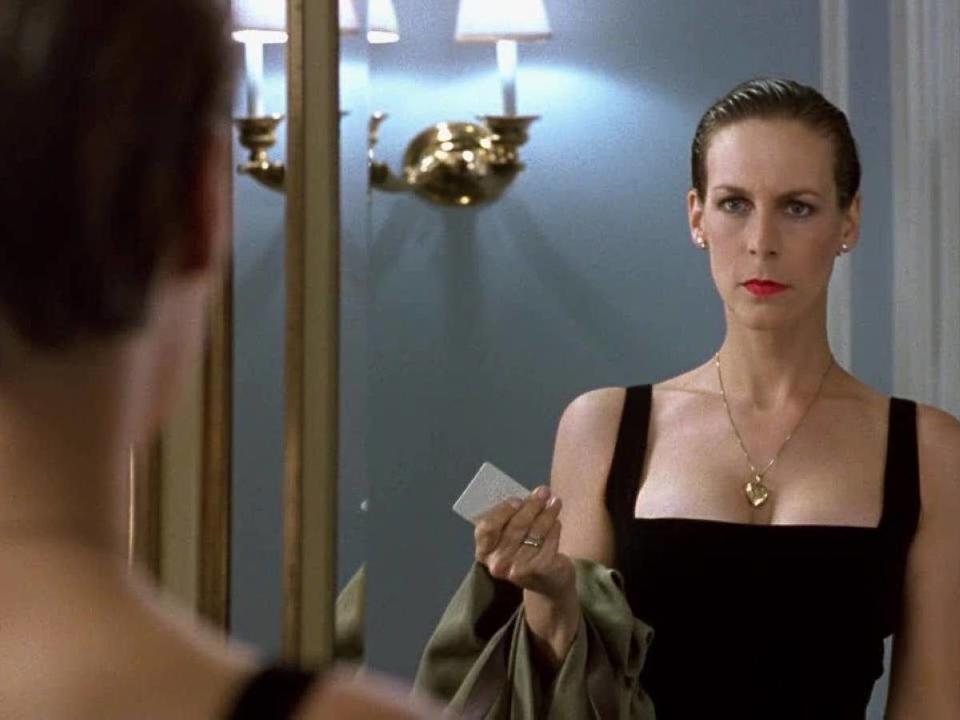 Jamie Lee Curtis in a black dress looking in the mirror