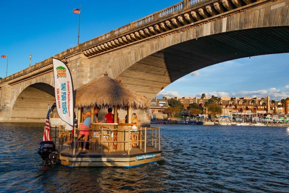 A floating tiki bar cruises past London Bridge for an outing on Lake Havasu.