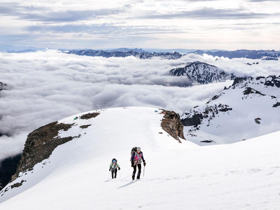 Two mountain climbers ascending snowy slope in Mount Rainier National Park.