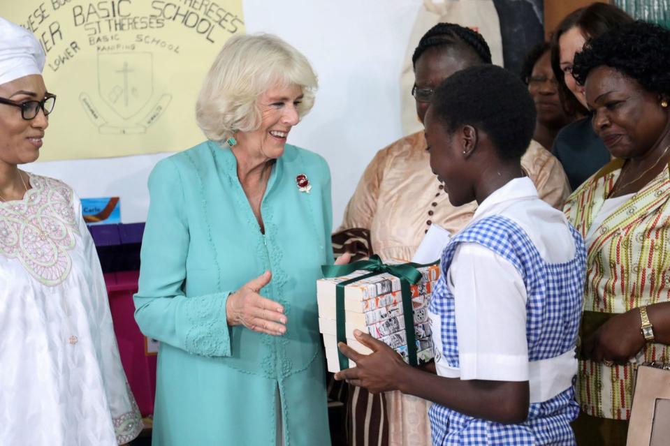 <p>The Duchess of Cornwall is greeted with a gift from a student as she visits St. Therese's School. While there, Camilla met students who are involved in an after school creative writing program. </p>
