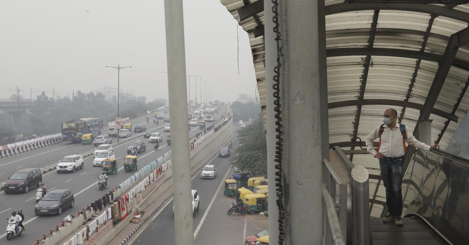 A commuter wars a pollution mask and crosses a foot over bridge with city enveloped in thick layer of smog in New Delhi, India, Thursday, Nov. 14, 2019. Schools in India's capital have been shut for Thursday and Friday after air quality plunged to a severe category for the third consecutive day, enveloping New Delhi in a thick gray haze of noxious air. (AP Photo/Manish Swarup)