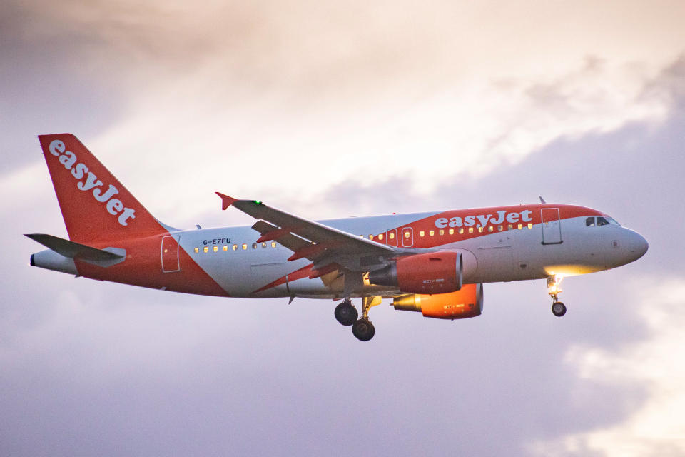 EasyJet Airbus A319 aircraft as seen on final approach flying and landing at Amsterdam Schiphol Airport AMS EHAM with the control tower and the airport terminal in the background in the evening. The arriving airplane of the British multinational low-cost airline has the registration G-EZFU. The aviation industry and passenger traffic is phasing a difficult period with the Covid-19 coronavirus pandemic having a negative impact on the travel business industry with fears of the worsening situation due to the new Omega variant mutation. Amsterdam, the Netherlands on January 5, 2022 (Photo by Nicolas Economou/NurPhoto via Getty Images)