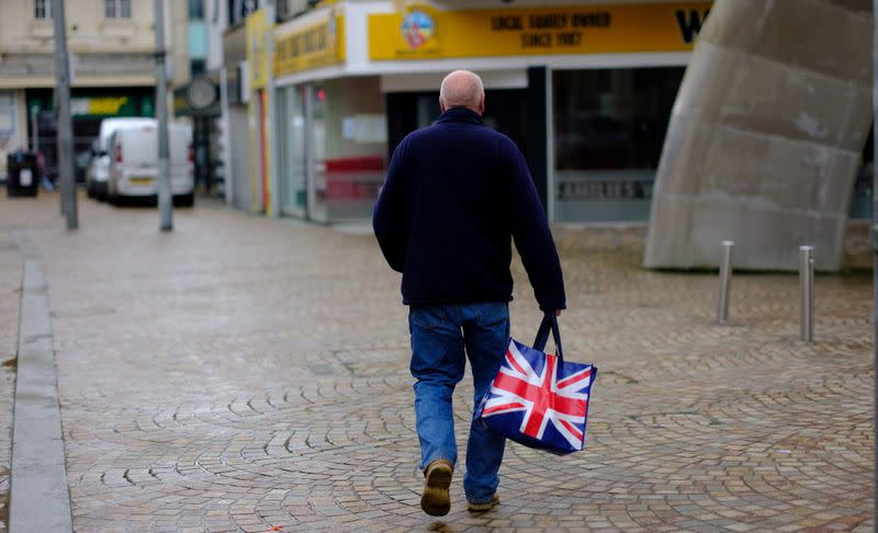 FILE PHOTO: A man carries a Union Jack themed shopping bag as he walks along an empty shopping street in Blackpool