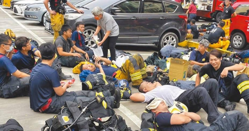 高雄鹽埕區「城中城」大樓發生大火，警消獲報後第一時間趕往現場搶救，搜救工作告一段落後，消防人員累癱在地。（圖／中國時報洪浩軒攝）