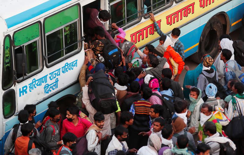 Migrant workers try to board a crowded bus as they return to their villages, during a 21-day nationwide lockdown to limit the spreading of coronavirus disease (COVID-19), in Ghaziabad