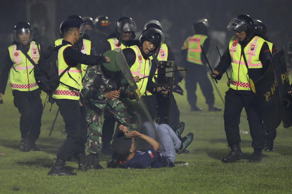 FILE - Security officers detain a fan during a clash between supporters of two Indonesian soccer teams at Kanjuruhan Stadium in Malang, East Java, Indonesia, Saturday, Oct. 1, 2022. (AP Photo/Yudha Prabowo, File)