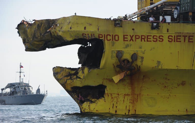 A Philippine navy boat guards a cargo ship with its bow destroyed on August 17, 2013, after it collided with the ferry St Thomas Aquinas the night before off the town of Talisay near the Philippines' second largest city of Cebu. Philippine rescuers searched on August 17 for 171 people missing