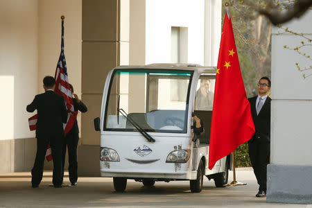 Officials carry Chinese and U.S. flags before a meeting of U.S. Secretary of State Rex Tillerson with Chinese officials outside the Diaoyutai State Guesthouse in Beijing, China, March 18, 2017. REUTERS/Thomas Peter