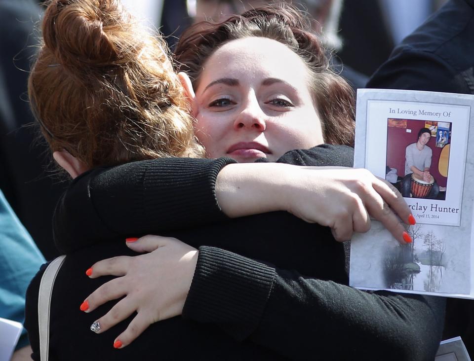 Friends hug after the funeral of Hunter in Calgary