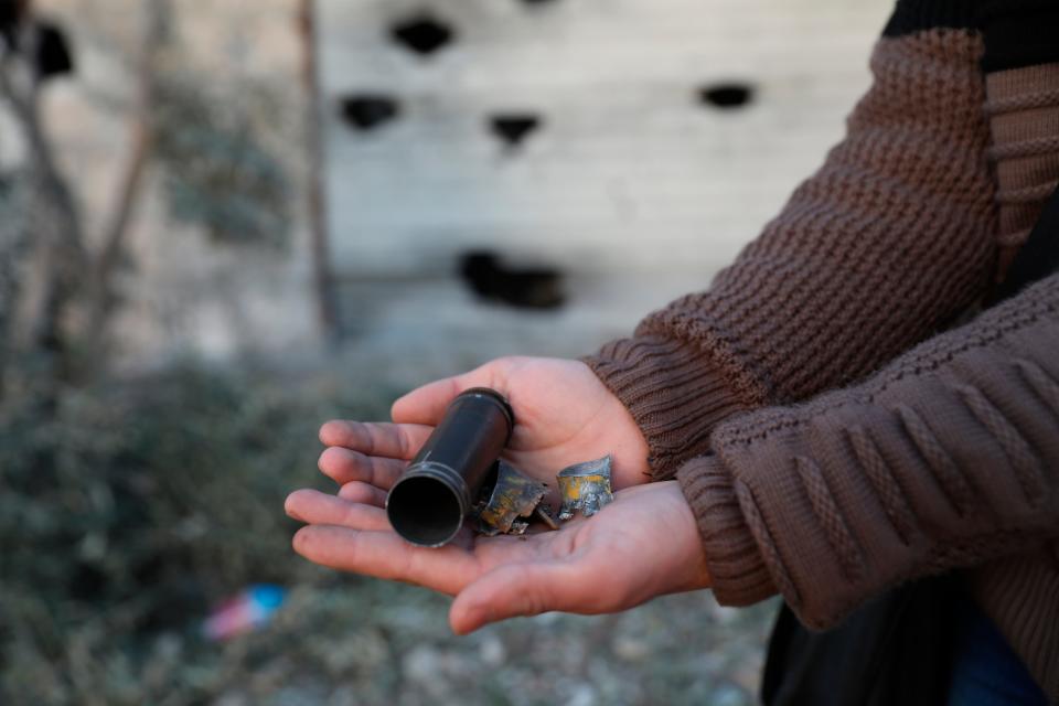 A child shows an empty bullet shell outside a destroyed house after an operation by the U.S. military in the Syrian village of Atmeh, in Idlib province, Syria, Thursday, Feb. 3, 2022 (AP)