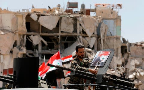 A member of the pro-government forces puts a portrait of the Syrian president on a military weapon - Credit:  LOUAI BESHARA/AFP