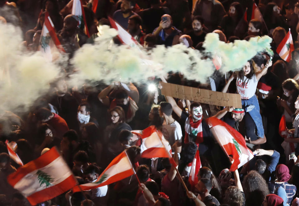 An Anti-government protester holds a lit flare during a protest, in Beirut, Lebanon, Wednesday, Oct. 23, 2019. Lebanese troops moved in to open major roads in Beirut and other cities Wednesday, scuffling in some places with anti-government protesters who had blocked the streets for the past week, grinding the country to a halt. (AP Photo/Hussein Malla)