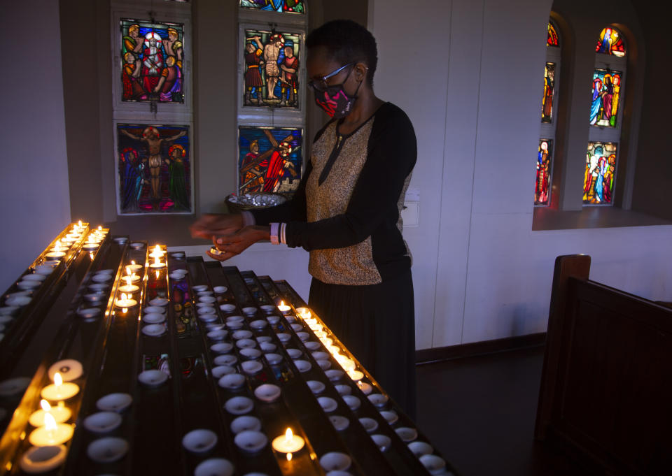 A worshipper wearing a face mask stands in front of lit candles prior to a morning Christmas Mass at the Rosebank Catholic Church in Johannesburg, Friday, Dec. 25, 2020. (AP Photo/Denis Farrell)