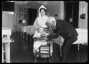 In this 1915-1923 photo made available by the Library of Congress, a doctor examines a child with a stethoscope, accompanied by a nurse, in the United States. Two centuries after its invention, the stethoscope _ the very symbol of the medical profession _ is facing an uncertain prognosis. It is threatened by hand-held devices that are also pressed against the chest but rely on ultrasound technology, artificial intelligence and smartphone apps instead of doctors’ ears to help detect leaks, murmurs, abnormal rhythms and other problems in the heart, lungs and elsewhere. (Harris & Ewing/Library of Congress via AP)