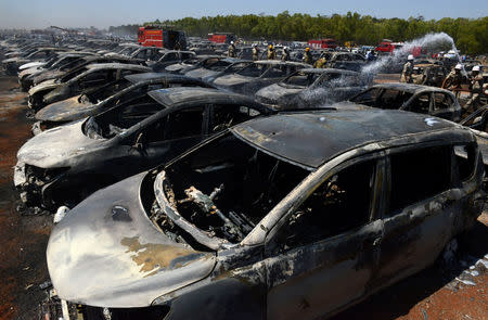 Firefighters extinguish smouldering cars after a fire broke out in a parking lot during the Aero India show at the Yelahanka Air Force Station in Bengaluru, India, February 23, 2019. REUTERS/Stringer