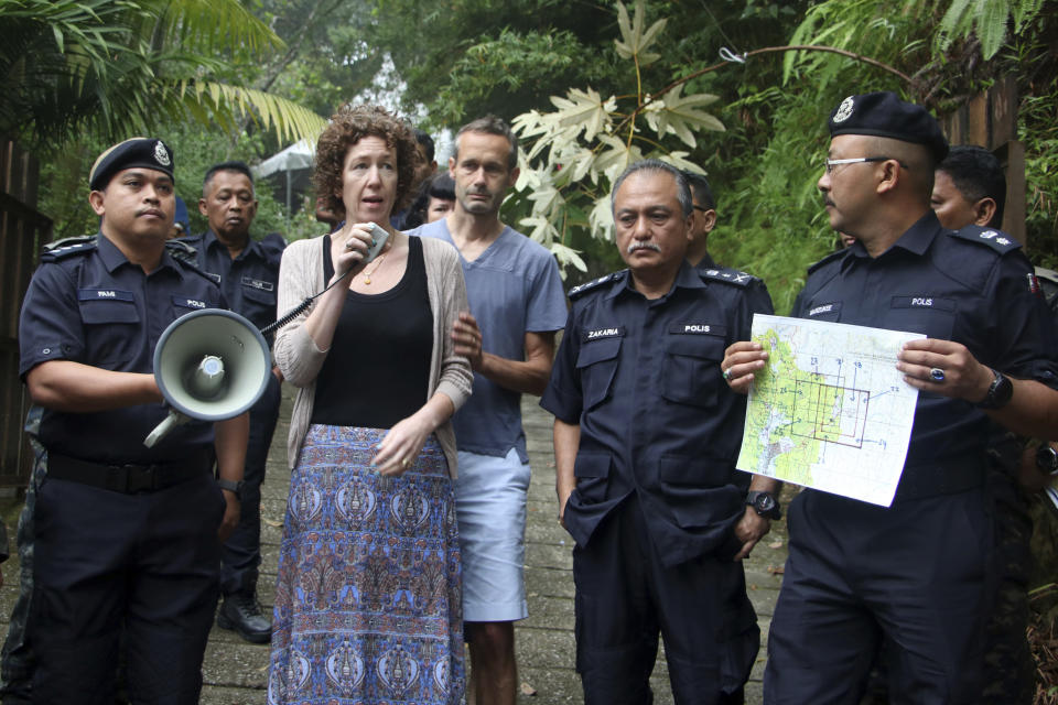 Meabh Quoirin, second left, the mother of a missing British girl Nora Anne Quoirin, speaks to police officers as father Sebastien Quoirin, center, stands beside her, in Seremban, Negeri Sembilan, Malaysia, Saturday, Aug. 10, 2019. The parents of the 15-year-old London girl who disappeared from a Malaysian resort a week ago say she isn't independent and has difficulty walking, in new details to support their conviction that she was abducted. (The Royal Malaysia Police via AP)