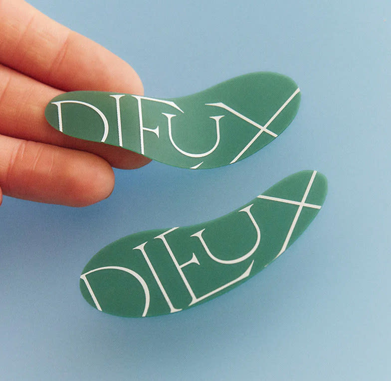 Green under-eye masks with Dieux's logo covering them in a thin, serif font