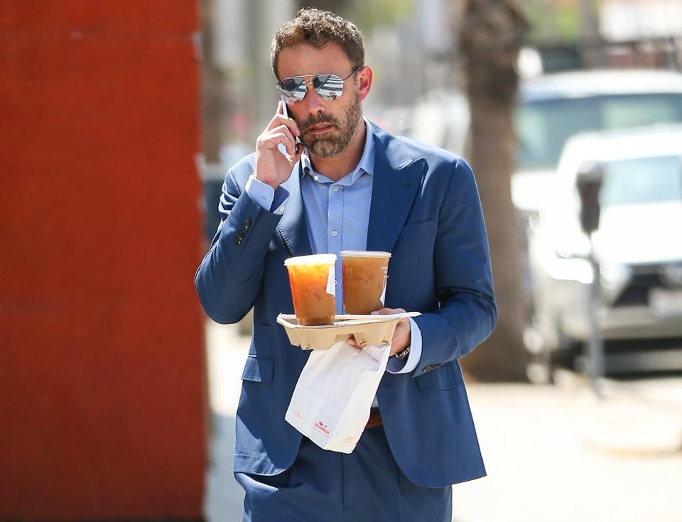 A closeup of Ben walking outside with coffee