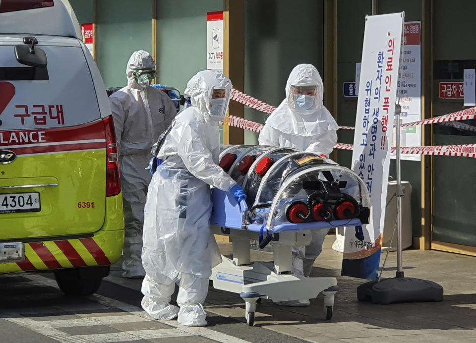 In this Wednesday, Feb. 19, 2020, photo, medial workers wearing protective gears move a patient suspected of contracting the new coronavirus from an ambulance to the Kyungpook National University Hospital in Daegu, South Korea. The mayor of the South Korean city of Daegu urged its 2.5 million people on Thursday, Feb. 20, to refrain from going outside as cases of a new virus spike. (Kim Jong-un/Yonhap via AP)