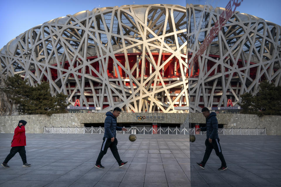 FILE - A man and a boy walk past the National Stadium, also known as the Bird's Nest, which will again be a venue for the 2022 Beijing Winter Olympics, in Beijing on Feb. 2, 2021. Ai is one of China's most famous artists, and many regard him as one of the world's greatest living artists. Working with the Swiss architectural firm Herzog & de Meuron, he helped design the Bird's Nest stadium, the centerpiece of Beijing's 2008 Summer Olympics. The stadium will also host the opening ceremony for Beijing's Winter Olympics on Feb. 4, 2022. (AP Photo/Mark Schiefelbein, File)